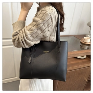 Close-up of black leather tote bag featuring 'FASHION & BAGS' text and dual shoulder straps