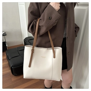 Detail of white leather tote bag with brown straps and engraved fashion typography