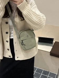 Sage green minimalist crossbody bag with adjustable strap and metallic M logo detail