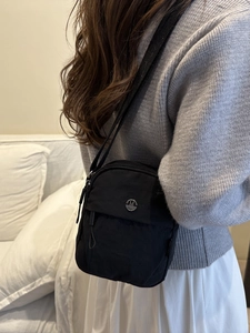 Minimalist black nylon crossbody bag for women with adjustable strap and metal logo