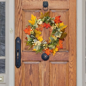 Fall harvest wreath with white pumpkins and maple leaves hanging on a dark wooden front door