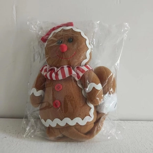 Detail of gingerbread man plush with red scarf and white wavy trim in packaging