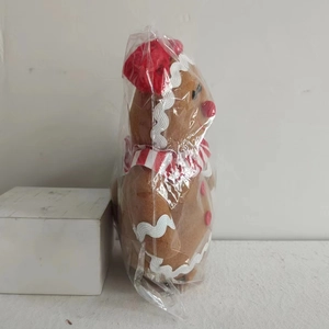 Gingerbread man plush toy in packaging with red hat and striped scarf detail