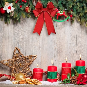 Close-up of red pillar candles with festive ribbons, cinnamon sticks and pine cones decor