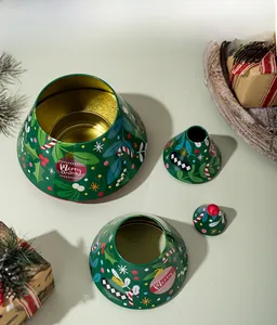 Detail of green Christmas tree tin box featuring festive prints and gold inner coating