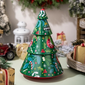 Detailed view of tree-shaped green tin box with Merry Christmas prints and holiday decor