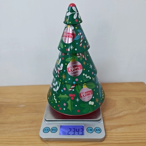 Detailed view of Christmas tree tin box on scale weighing approximately 234 grams