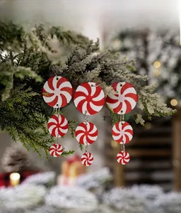 Detail of red and white peppermint swirl earrings hanging on a Christmas tree branch