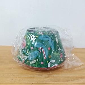 Detail of Christmas tree shaped tin box featuring festive holly and snowflake patterns