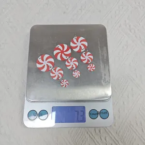 Macro detail of three pairs of red and white peppermint candy earrings on a scale