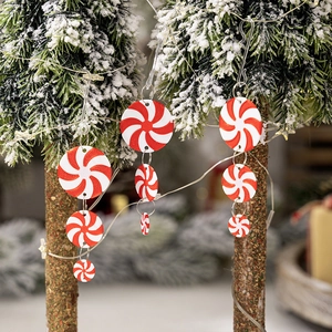 Red and white swirl peppermint candy Christmas tree hanging ornaments on snowy branches