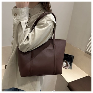 Detailed close-up of dark brown tote bag featuring matte leather and curved panel stitching