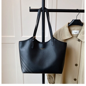 Detail of black leather tote bag with gold lettering and adjustable metal buckle handle