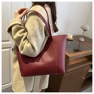Detailed view of the double stitching and matte leather texture on a deep red tote bag