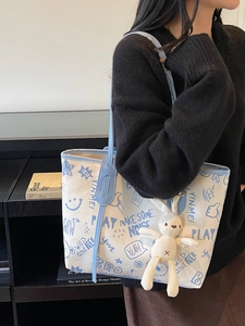 White canvas tote bag with blue graffiti lettering and cute plush rabbit charm accessory