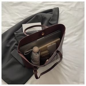 Top view of deep red leather tote bag interior showing laptop and daily essentials