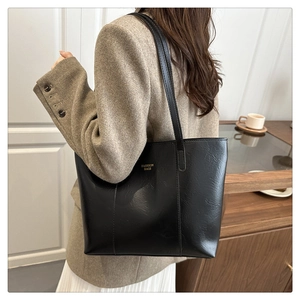 Detail of black PU leather tote bag with gold lettering and decorative stitching