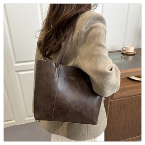 Detail of vintage texture coffee brown tote bag with gold lettering and slim strap