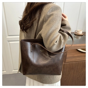 Detail of a large brown tote bag showing glossy PU leather and FASHION BAGS gold lettering