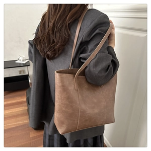 Detail of vintage brown PU leather tote bag with elegant vertical stitching and long straps