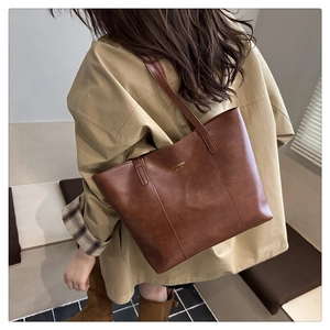 Detail view of brown leather tote bag with golden Fashion Bags text and shoulder strap
