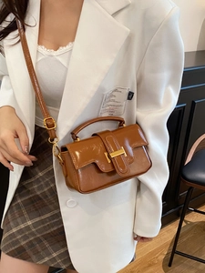 Sac bandoulière vintage marron avec boucle dorée porté par un mannequin femme