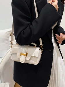 Sac carré minimaliste en cuir verni beige avec boucle H dorée porté par mannequin