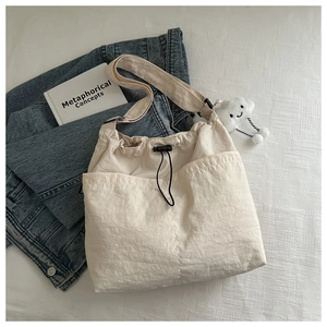 Detail of minimalist cream drawstring crossbody bag with plush cloud charm and strap