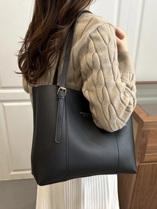 French style black faux leather tote bag with gold lettering shown on shoulder by model