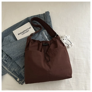 Detail of dark brown nylon crossbody bag with drawstring closure and cloud charm