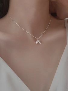 Nahaufnahme einer eleganten silbernen Schleifenkette am Hals einer Frau für einen trendigen Look