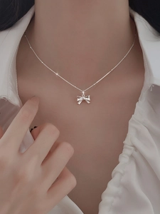 Nahaufnahme einer silbernen Schleifenkette an einem Modell mit minimalistischer Kugelkette