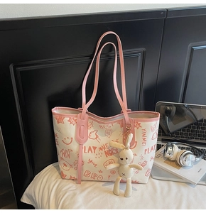 Detailed view of a white tote bag with bear graffiti prints and plush rabbit charm