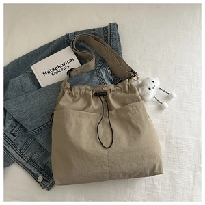 Detailed view of khaki drawstring crossbody bag with soft plush cloud charm and strap