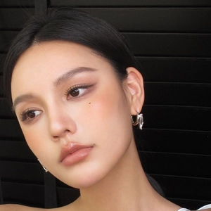Close-up of a silver C-shaped hoop earring with a marquise zircon on a model