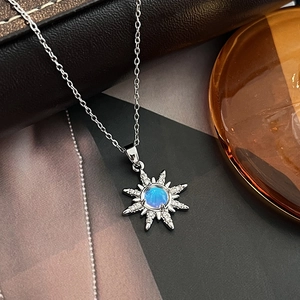 Detailed shot of a silver starburst pendant necklace with a blue gemstone on dark leather