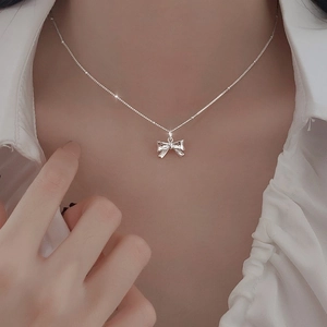 Elegante Halskette mit silbernem Schleifenanhänger an Model, glänzender Modeschmuck