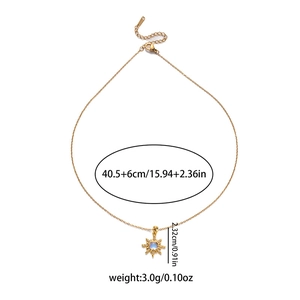 Golden sunburst star necklace with blue center stone and white rhinestones on white background