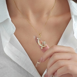 Elegant gold moon and star pendant necklace with cubic zirconia on a female model