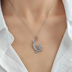 Close-up of silver star and crescent moon necklace featuring shimmering zircon micro-inlay