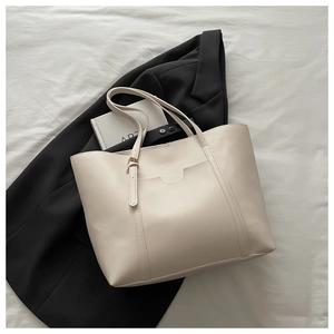 Detail of cream leather tote bag with elegant side buckle on soft textured background