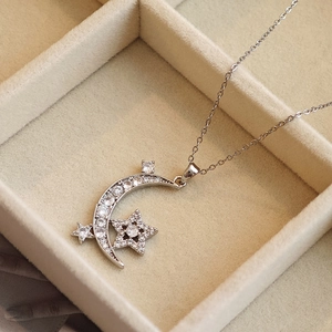 Chic silver star and moon pendant necklace with sparkling zircons on a velvet cushion