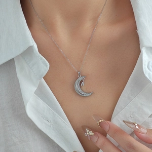 Detail of silver crescent moon necklace with teardrop pendant and micro-pave zircons