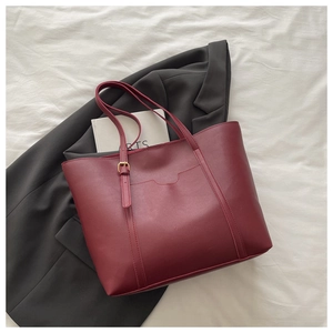 Detail view of burgundy leather tote bag with gold buckle and functional front pocket
