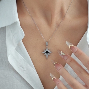 Detail of starburst necklace with black gemstone and white zircons on white shirt