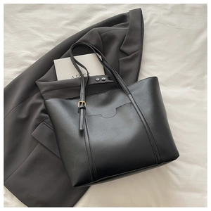 Detail of black faux leather tote bag with gold buckle and stylish top-stitched pocket