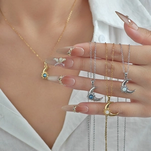 Close-up of crescent moon pendant necklaces with blue and opal stones in gold and silver
