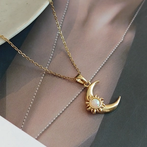 Elegant gold celestial necklace featuring a sun and moon pendant with white opal inlay