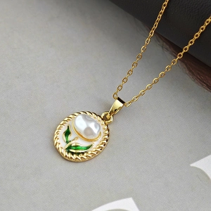 Dettaglio della collana d'oro vintage con pendente floreale in smalto bianco e perla