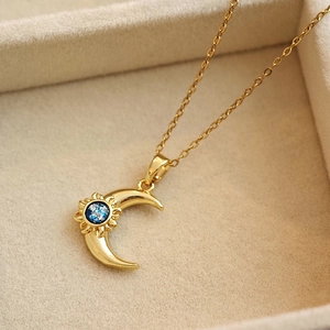 Golden sun and moon necklace with blue celestial stone displayed in a jewelry box
